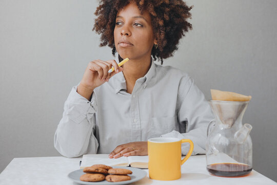 Сurly African-American woman is having breakfast and writing a diary.