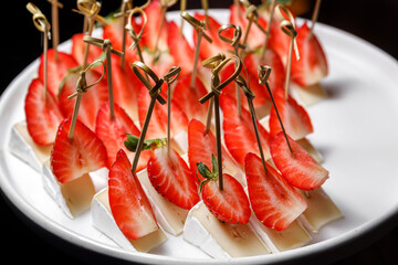Canapes with brie cheese and ripe sliced strawberries.