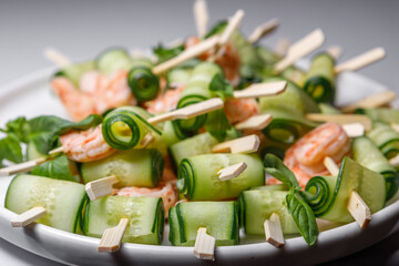 Canapes with cucumber and shrimp on a large plate.