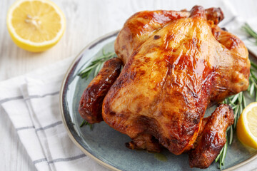 Homemade Lemon and Herb Rotisserie Chicken on a Plate, low angle view. Close-up.
