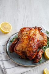 Homemade Lemon and Herb Rotisserie Chicken on a Plate, side view. Copy space.