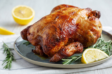 Homemade Lemon and Herb Rotisserie Chicken on a Plate, side view. Close-up.