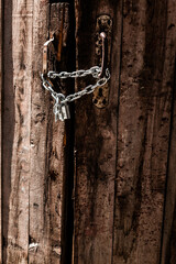 Old door with lock and chain in bright sunlight, vertical frame