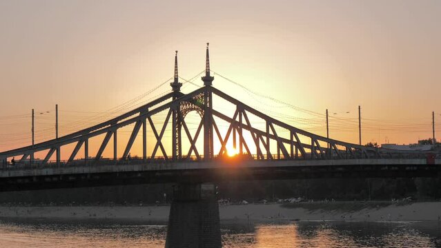 Side view of the road bridge across the river against the sun at sunset. Beautiful cityscape