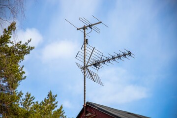 Low angle shot of TV antennas over building in background of blue sky