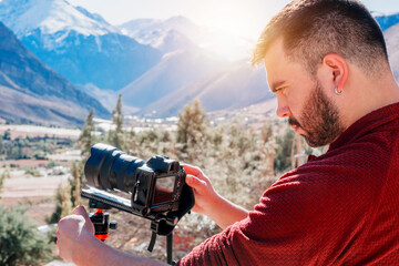 young latin photographer looking and holding a photo camera outdoors over a valley, Elqui Valley