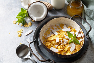 Vegan healthy breakfast. Cereal granola breakfast flakes with coconut non-dairy alternative milk and fresh coconut slices on a stone tabletop. Copy space.