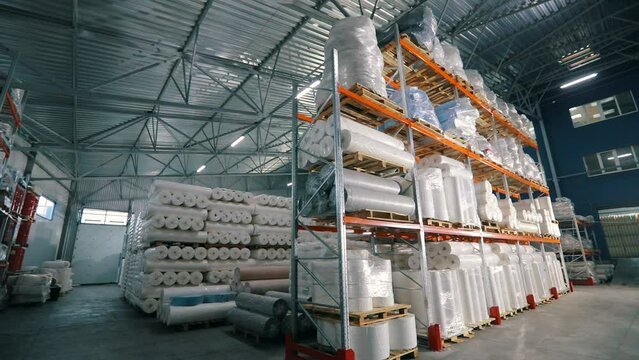 Large modern warehouse in the factory. Large warehouse in a nonwovens factory. Industrial interior. Lots of big rolls of spunbond. Warehouse with rolls of nonwovens.
