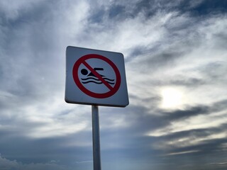 No swimming warning sign with blue sky in the background