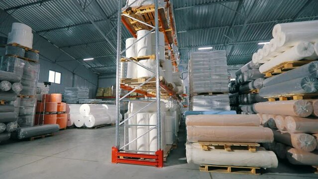 Large modern warehouse in the factory. Large warehouse in a nonwovens factory. Industrial interior. Lots of big rolls of spunbond. Warehouse with rolls of nonwovens.