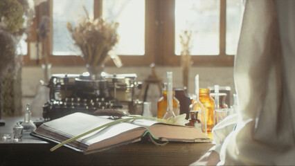A man writer dips his pen into an inkwell and prepares to write a book in his workshop. Cosplay of the Middle Ages. Cinematic concept. Close-up feather