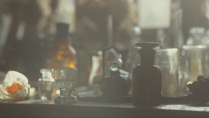 Close-up of a perfumer's workplace. Vintage cinematic concept. Sunny day in the working workshop. Lots of ingredients, a book, glass flasks on the table. Depth of field