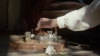 A man's hand plays chess with flasks on a chessboard. The concept of a perfumer, relaxation,...