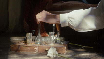 A man's hand plays chess with flasks on a chessboard. The concept of a perfumer, relaxation, creative crisis, reflection, play, invention. Cinematic concept