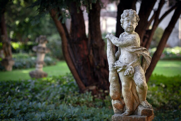 stone statue corroded by time in a romantic garden of an ancient palace in Mantua in the background of a tree