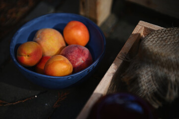 Focus on ripe apricots from organic farm in blue ceramic bowl next to a wooden box with homemade jam jars. Healthy food