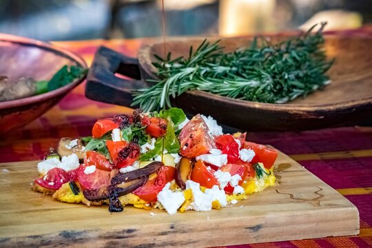 Tasty Mexican salad with peppadew, cheese, tomatoes, and sliced  mushrooms on a wooden board