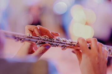 Closeup view of the hands of a woman playing the flute - woodwind instrument © Fotoe Commerce/Wirestock Creators