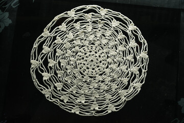 beautiful white tablecloth for centerpiece hand-knitted with crochet technique. centerpiece folder knitted in wool with heart shapes, round centerpiece on transparent glass table - obrazy, fototapety, plakaty