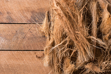 coconut husk fiber or coir on wooden table top, commercially important natural fiber extracted from outer husk of coconut fruit, taken from above with space for text