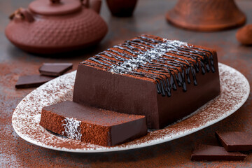 Sliced chocolate jelly pudding or mousse cake on a white plate with chocolate sauce and sprinkle of...