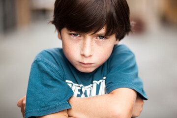 angry boy in the street with his arms crossed and with a gesture of disgust. Portrait of angry boy...