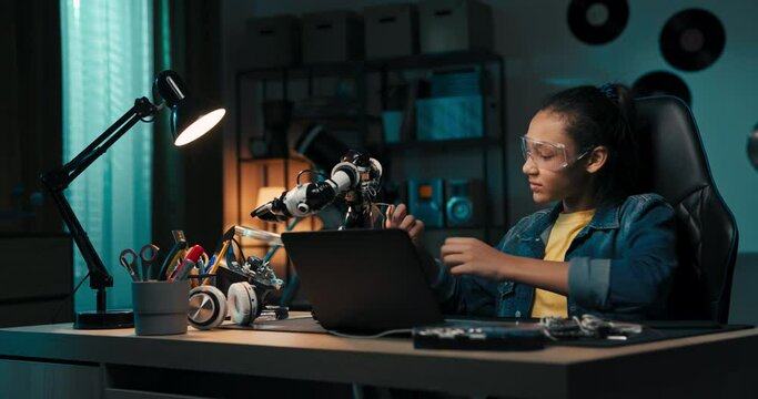 Portrait of a girl wearing safety glasses engaged in soldering a robot, child develops new skills, solders cables, electrical wires, repairs damage.