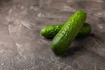 Fresh cucumbers on a white black texture background. Vegetarian organic vegetables.Ingredient for salad. Healthy food.Copy space.Place for text