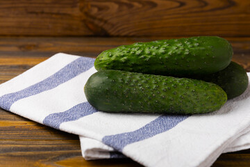 Fresh organic cucumbers on a brown wooden table. Salad ingredient. Fresh vegetables. Vegan food. Healthy food. Fresh organic vegetables.