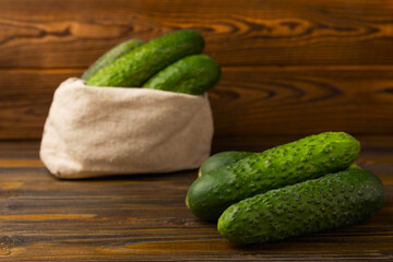 Fresh organic cucumbers on a brown wooden table. Salad ingredient. Fresh vegetables. Vegan food. Healthy food. Fresh organic vegetables.