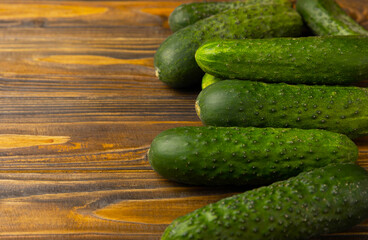 Fresh organic cucumbers on a brown wooden table. Salad ingredient. Fresh vegetables. Vegan food. Healthy food. Fresh organic vegetables.