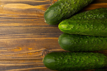 Fresh organic cucumbers on a brown wooden table. Salad ingredient. Fresh vegetables. Vegan food. Healthy food. Fresh organic vegetables.