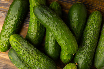 Fresh organic cucumbers on a brown wooden table. Salad ingredient. Fresh vegetables. Vegan food. Healthy food. Fresh organic vegetables.