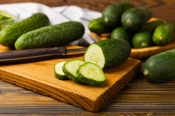 Fresh organic cucumbers on a brown wooden table.Cucumber slices. Salad ingredient. Fresh vegetables. Vegan food. Healthy food. Fresh organic vegetables.