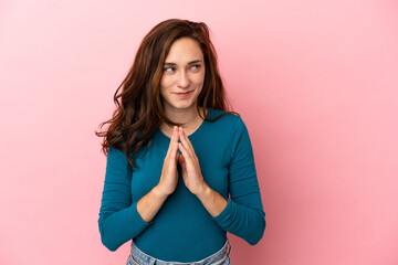 Young caucasian woman isolated on pink background scheming something