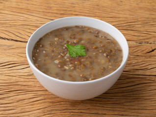 Lentil soup in a bowl with seasoning over wooden table