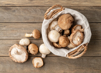 Shitake, portobello and paris mushrooms in a basket over wooden table