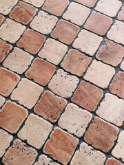 The worn stone floor is made of two-colored tiles in a checkerboard pattern diagonally. View from above