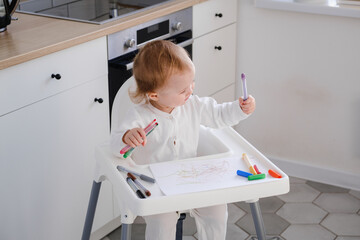Cute toddler having fun drawing his first scribbles using colored felt-tip pens. Baby learning to draw.