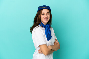 Airplane stewardess woman isolated on blue background with arms crossed and looking forward