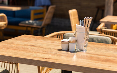 Cutlery and white napkins in a beer mug on a table in a street cafe