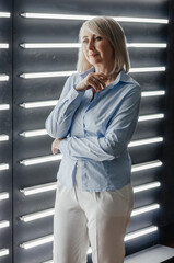 a woman in a blue shirt near a wall with backlight