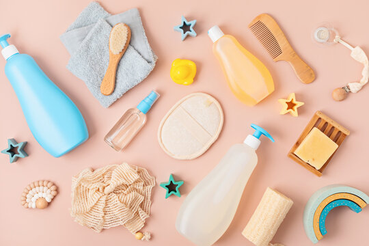 Set of baby toiletries, child organic hygiene and bath accessories, shower gel, shampoo, essential oil, towel on pink pastel background. Top view, flatlay