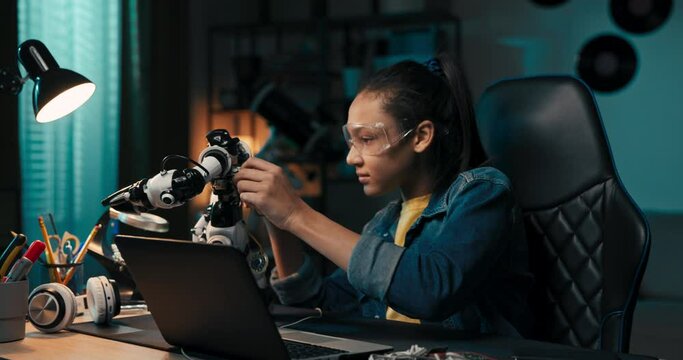 Girl fascinated by electronics watches robot, plays with toy. The room at night, illuminated by a blue glow in the evening.