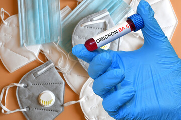 The doctor holds a blood test tube for the detection of the Omicron BA.5 Variant of the Covid-19 virus with various protection masks on the background - obrazy, fototapety, plakaty