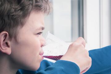 A little boy drinks from a glass