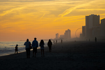 People walking on a beach at sunset