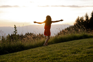 Mädchen, 8 Jahre, springt in einer Wiese bei Sonnenuntergang, Kärnten, Österreich