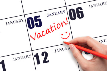 A hand writing a VACATION text and drawing a smiling face on a calendar date 5 January. Vacation...