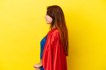 Super Hero redhead woman isolated on yellow background in lateral position